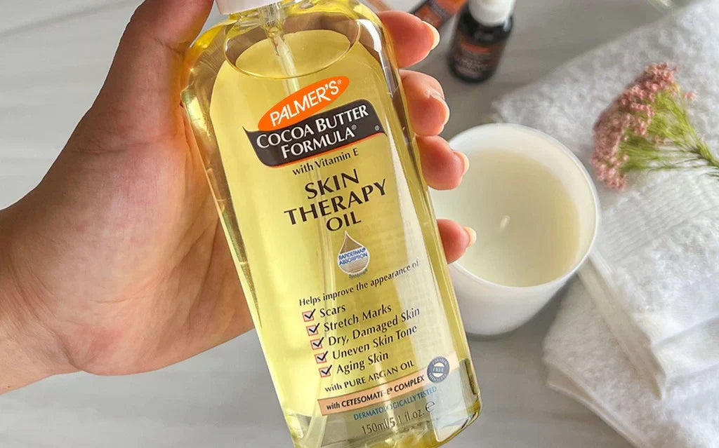 A hand holding a bottle of skin therapy oil, showcasing the product's label and design in a close-up view.